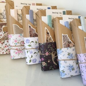 May include: A collection of wrapped gifts with floral patterned paper. Each gift is tied with twine and includes a small notebook with the words "Reading Log" on the cover.