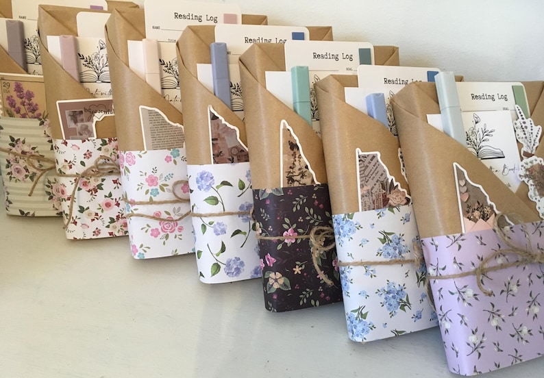 May include: A collection of wrapped gifts with floral patterned paper. Each gift is tied with twine and includes a small notebook with the words "Reading Log" on the cover.