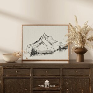 A timeless digital mountain sketch print designed for elegant, nature-inspired interiors. This printable wall art brings a calm, vintage feel to living rooms, bedrooms, offices, and cabin spaces.Vintage printable mountain wall art shown in a dark wood frame, featuring a black and white landscape sketch on a neutral background.Vintage printable mountain wall art shown in a dark wood frame, featuring a black and white landscape sketch on a neutral background.