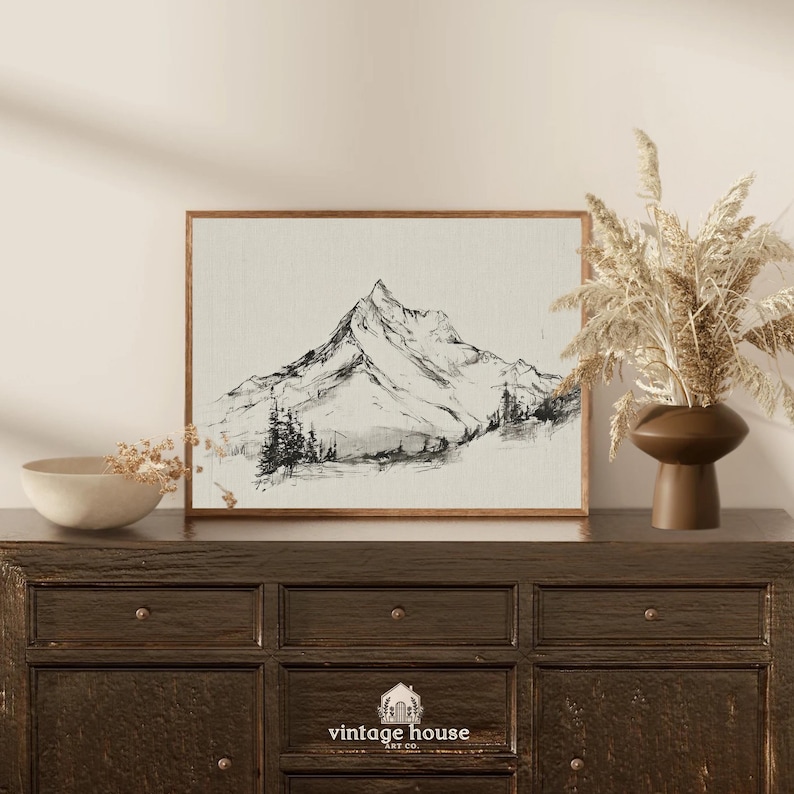 A timeless digital mountain sketch print designed for elegant, nature-inspired interiors. This printable wall art brings a calm, vintage feel to living rooms, bedrooms, offices, and cabin spaces.Vintage printable mountain wall art shown in a dark wood frame, featuring a black and white landscape sketch on a neutral background.Vintage printable mountain wall art shown in a dark wood frame, featuring a black and white landscape sketch on a neutral background.