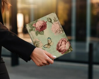 May include: A teal blue journal with a floral design featuring pink and red roses and a butterfly. The journal has a vintage aesthetic.