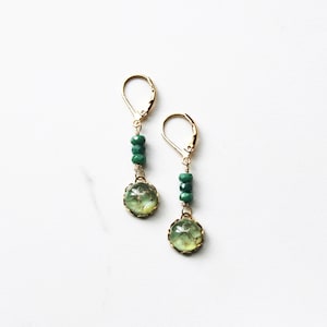 Green drop earring featuring three faceted emeralds and a luminous vintage green glass stone that is set in a brass setting.