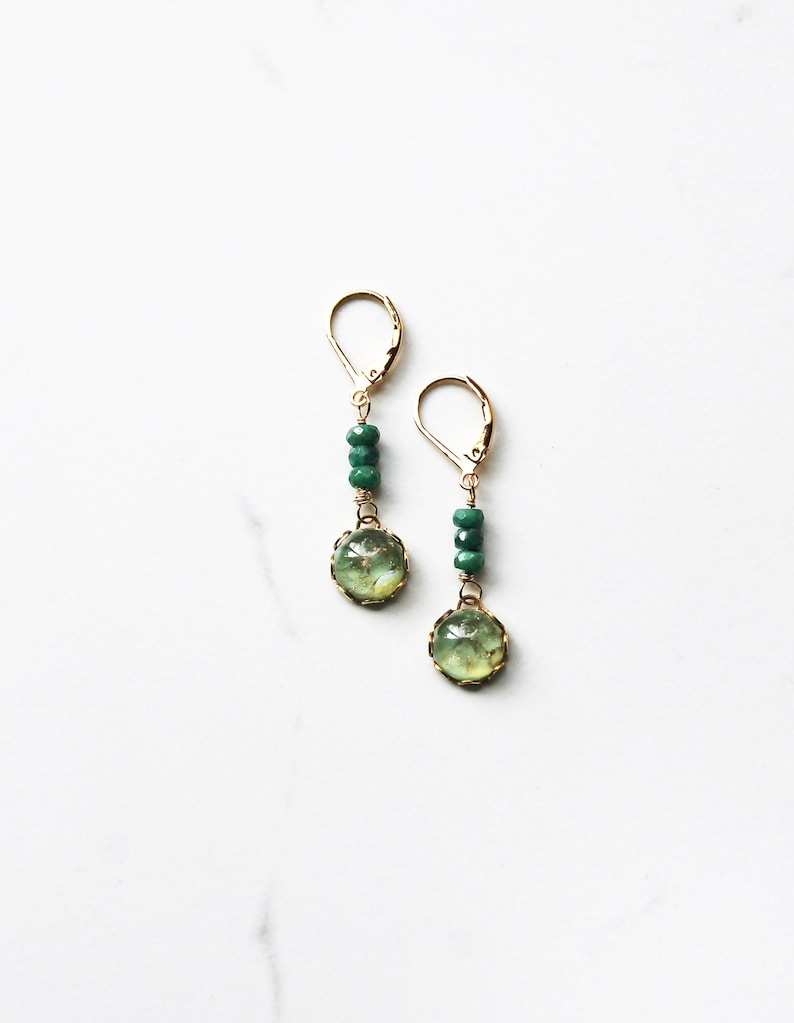 Green drop earring featuring three faceted emeralds and a luminous vintage green glass stone that is set in a brass setting.