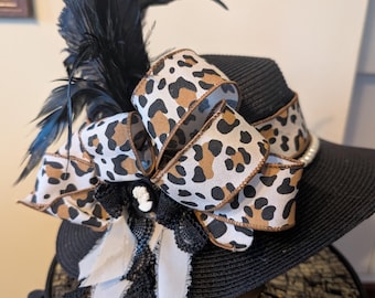 Sombrero negro acentuado con plumas negras, perlas y lazo/cinta de guepardo.
