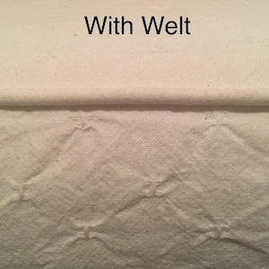 May include: Close-up of a white fabric with a welt seam. The fabric has a quilted pattern with diamond shapes.