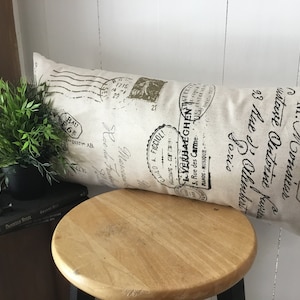 May include: A beige pillow with black text and stamps. The text includes "M. Monsieur Gustave Antoine Kureg 93 Rue de limber Soris CARLO A. FICCIOL! 21 MINOS-MUSIQUE. 3. Rue des Carme VERHAEGHEN"