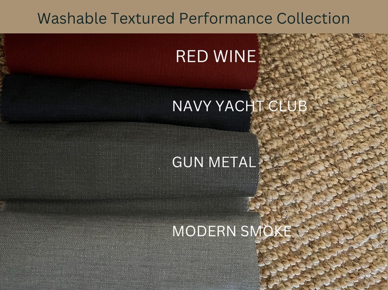 May include: Fabric swatches in shades of red wine, navy, gun metal, and modern smoke are displayed. The text reads "Washable Textured Performance Collection". The swatches are presented against a textured, neutral background.