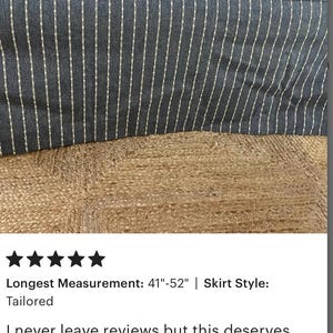 May include: A large, rectangular ottoman with a dark gray fabric cover featuring vertical white stripes. The ottoman's longest measurement is between 41 and 52 inches. The ottoman is on a woven jute rug.