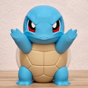 Op de afbeelding: Een blauwe Squirtle-figuur met een lichtbruin schild en witte accenten. De figuur heeft rode ogen en de armen zijn uitgestrekt. Dit is een verzamelobject uit de populaire Pokémon-franchise.