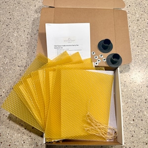 May include: A candle-making kit with yellow beeswax sheets, wicks, candle holders, and googly eyes. The kit includes instructions and is packaged in a cardboard box. The beeswax sheets have a honeycomb pattern.