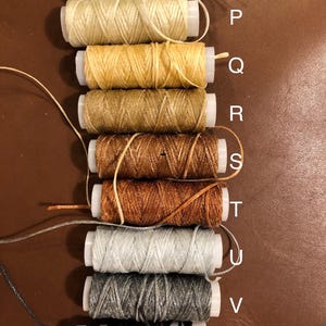 May include: Nine spools of waxed thread in various colors, including white, beige, yellow, brown, orange, gray, and black. The spools are labeled with letters from O to W.