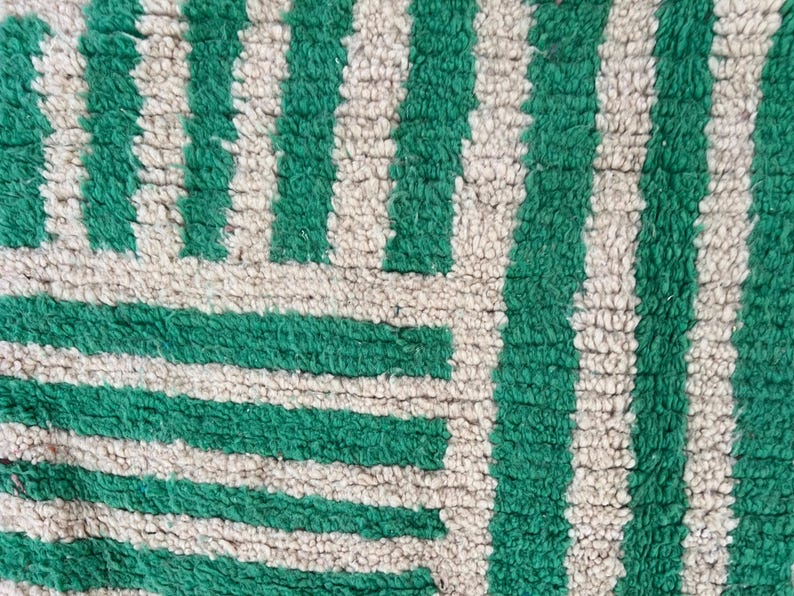 Pode incluir: Close-up de um tapete texturizado com um padr&atilde;o repetitivo de listras verdes verticais alternando com listras bege. O design do tapete tamb&eacute;m apresenta listras verdes horizontais, criando um padr&atilde;o geom&eacute;trico. O tapete tem uma apar&ecirc;ncia macia e felpuda.
