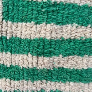Pode incluir: Close-up de um tapete texturizado com listras verdes e branco-sujo alternadas. O tapete tem uma pilha espessa e macia, e as cores s&atilde;o vibrantes. O design &eacute; simples e moderno, adequado para decora&ccedil;&atilde;o de casa.