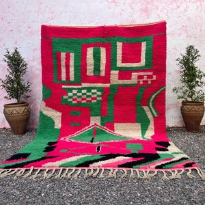 May include: A vibrant, geometric rug with a bold color palette. The rug features a striking combination of red, green, white, and black. The design includes rectangular and angular shapes, with a fringed edge. This decorative rug is a statement piece for any room.
