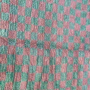 May include: A checkered fabric with alternating squares of green and brown. The fabric has a fuzzy texture.
