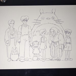 May include: A black and white line drawing of a group of characters from the animated film 'My Neighbor Totoro'. The characters are standing in front of a large, furry creature with big eyes. The creature is Totoro, a friendly forest spirit.
