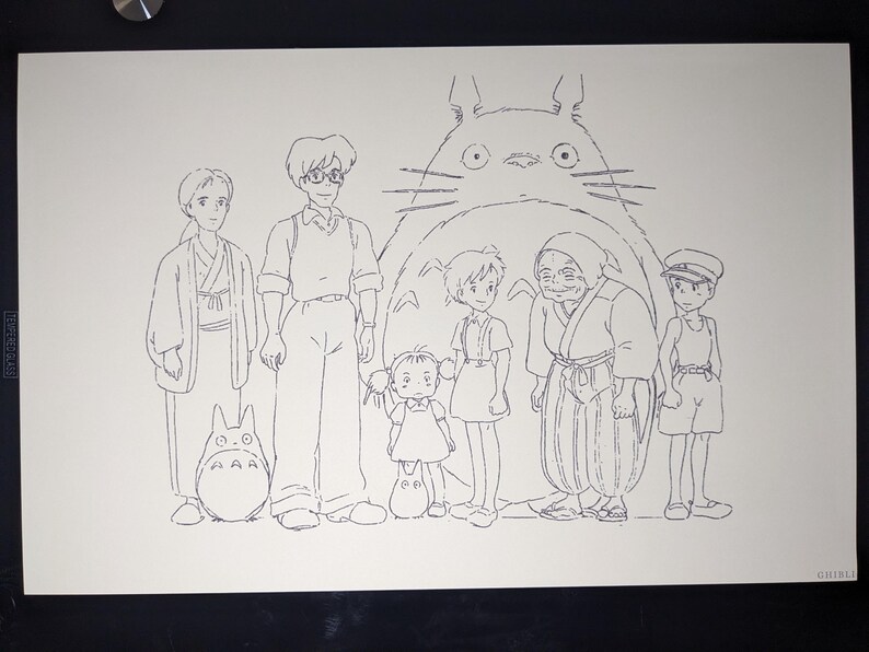 May include: A black and white line drawing of a group of characters from the animated film 'My Neighbor Totoro'. The characters are standing in front of a large, furry creature with big eyes. The creature is Totoro, a friendly forest spirit.