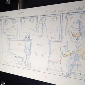 May include: A black and white hand-drawn illustration of three characters on a train. The characters are a young girl with short hair, a faceless spirit with a large, white, mask-like head, and a man wearing a hat and a coat. The illustration is on a white background with blue and red lines.