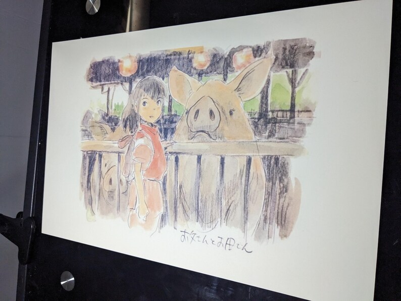 May include: A watercolor illustration of a young girl with long dark hair, wearing a red shirt, standing in front of a fence with a pig behind it. The pig is looking at the girl. The illustration is signed "おとなの子供" in Japanese.