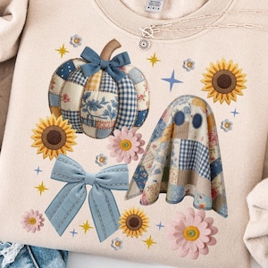 Puede incluir: Sudadera beige con un diseño de calabaza y fantasma de patchwork, girasoles, lazos y detalles florales. El diseño incluye colores azul, blanco y amarillo. La sudadera se combina con unos vaqueros rotos de color azul claro.