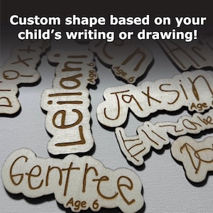 May include: Close-up of several wooden name tags with custom shapes based on children's handwriting. The names "Leilani", "Jaxsin", and "Gentry" are visible, along with the age "6" written on each tag.