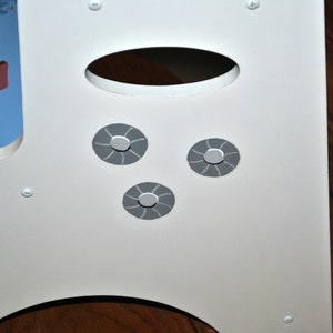 Pu&ograve; includere: Struttura di gioco in legno bianco per bambini con tre cerchi dipinti di grigio con un motivo a spirale.