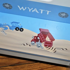 Pu&ograve; includere: Uno sgabello a gradini in legno blu e bianco con un piano superiore blu chiaro. Il piano superiore &egrave; dipinto con un camion ribaltabile rosso e un escavatore blu. Lo sgabello &egrave; personalizzato con il nome "WYATT" in lettere bianche.