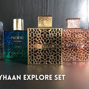 May include: An assortment of perfume bottles with intricate geometric designs. The bottles are in various colors, including silver, gold, and copper, with the text "RAYHAAN EXPLORE SET" at the bottom. The bottles have different names like "PACIFIC" and "ADONIS".
