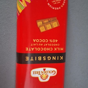 May include: A red Kingsbite milk chocolate bar with a colorful patterned top. The packaging includes the text "40% Cocoa" and "100g". The Golden Tree logo is visible.