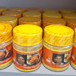 May include: A close-up of several yellow jars of seasoning blend. The jars have a yellow lid and a label with a picture of a roasted chicken and the text "Give Awards" and "Westlife Royal Blend".