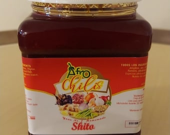 May include: A jar of Afro Chilis Shito, a homemade product. The jar has a white lid and a red label with text and illustrations of ingredients. The contents are a dark, reddish-brown color.