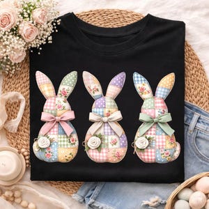 May include: Black t-shirt featuring three patchwork bunny designs. Each bunny has a bow and a floral accent. The bunnies are made of pastel-colored squares and floral patterns, perfect for Easter or spring.