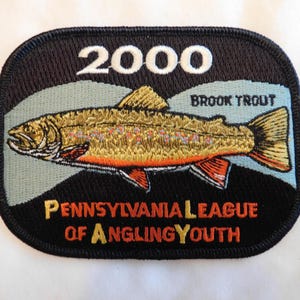 May include: Embroidered patch featuring a brook trout with orange, yellow, and brown details. The patch includes the year "2000" and the text "Pennsylvania League of Angling Youth" in white and yellow lettering.
