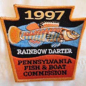 May include: Embroidered patch featuring a colorful rainbow darter fish. The patch has a black background with the text "1997" at the top and "RAINBOW DARTER" below the fish. The bottom text reads "PENNSYLVANIA FISH & BOAT COMMISSION".