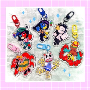 Peut inclure: Une collection de porte-clés en acrylique colorés représentant des personnages de dessins animés. Chaque porte-clés a un design unique avec des couleurs vives et des fermoirs en métal. Les porte-clés sont présentés sur un fond à carreaux rose et blanc.