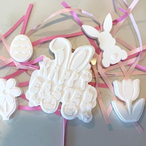 Puede incluir: Taza de cerámica blanca con asa negra y la frase "But First, Coffee" en negro. La taza se muestra sobre un fondo borroso, sugiriendo un ambiente acogedor.