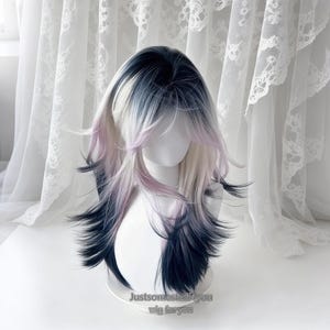 Puede incluir: Una peluca larga y en capas con una mezcla de colores, incluyendo negro, blanco y lavanda. La peluca está peinada con flequillo y mechones largos y sueltos. El texto "Justsomestuff4you wig foryou" es visible.