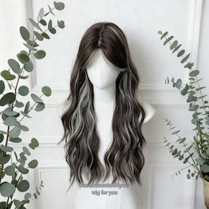 Op de afbeelding: Een lange, golvende pruik met donkerbruine en grijze highlights, tentoongesteld op een mannequinhoofd. De pruik heeft een middenscheiding en gezichtsverfraaiende lagen. De tekst "justsomestuff4you wig for you" is zichtbaar onderaan.