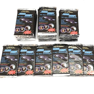 Könnte beinhalten: Eine Sammlung von neun versiegelten Star Trek The Next Generation Stardiscs-Folienpackungen, die in zwei Reihen angeordnet sind. Jede schwarze rechteckige Packung zeigt das Star Trek-Logo, eine Grafik der USS Enterprise und kreisförmige Charakterporträts.