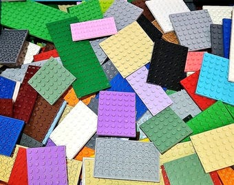 May include: A pile of colorful plastic building blocks in various shapes and sizes. The blocks are in shades of green, pink, purple, yellow, red, blue, white, gray, and brown. The blocks have a textured surface with circular studs.