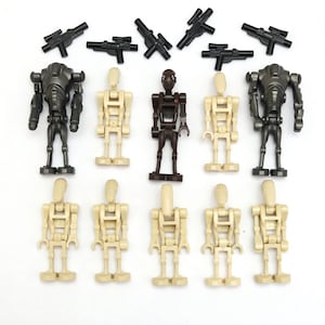 May include: A collection of twelve plastic toy robot figures and six black plastic toy blasters. The set includes two dark gray super battle droids, nine tan battle droids, and one dark brown battle droid, all standing in two rows.