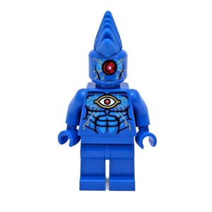 May include: A blue Lego minifigure with a pointed head and a single red eye. The figure has a detailed design on its chest and face, featuring an eye symbol and intricate patterns. The toy is a collectible item.