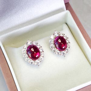 Pendientes de botón con cabujón de rubí sangre de paloma de talla ovalada de 3,5 quilates con halo de diamantes simulados, plata S925 con baño de oro blanco.