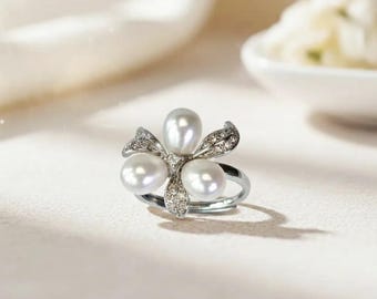 Elegante anillo con motivo floral, perlas naturales de agua dulce y detalles de circonitas cúbicas, chapado en oro blanco de 18 quilates.