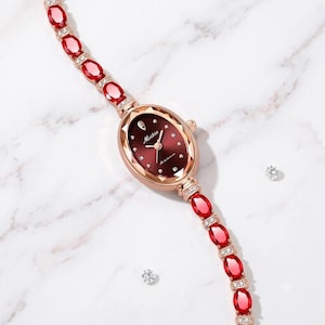 Relógio feminino com caixa oval, mostrador vermelho escuro e pulseira | Detalhes em rubi oval e diamante simulado de lapidação redonda | Banhado a ouro rosa 18K | Presente para ela