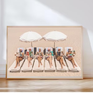 May include: A framed print depicting six people lounging on beach chairs, reading magazines beneath striped parasols. The image is set on a sandy beach with a light colour palette, creating a serene and summery atmosphere.
