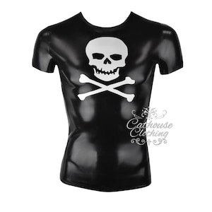 Puede incluir: Camiseta negra con un diseño de calavera y huesos cruzados blancos. La camiseta tiene cuello redondo y mangas cortas. El texto "Cathouse Clothing" está impreso en la parte inferior derecha.