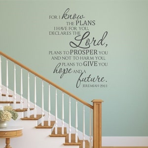 Puede incluir: Una calcomanía de pared con una cita de Jeremías 29:11, "Porque yo sé los planes que tengo para vosotros, declara Jehová, planes de bien y no de mal, para daros un futuro y una esperanza." La calcomanía está en una pared verde claro con una escalera de madera blanca.