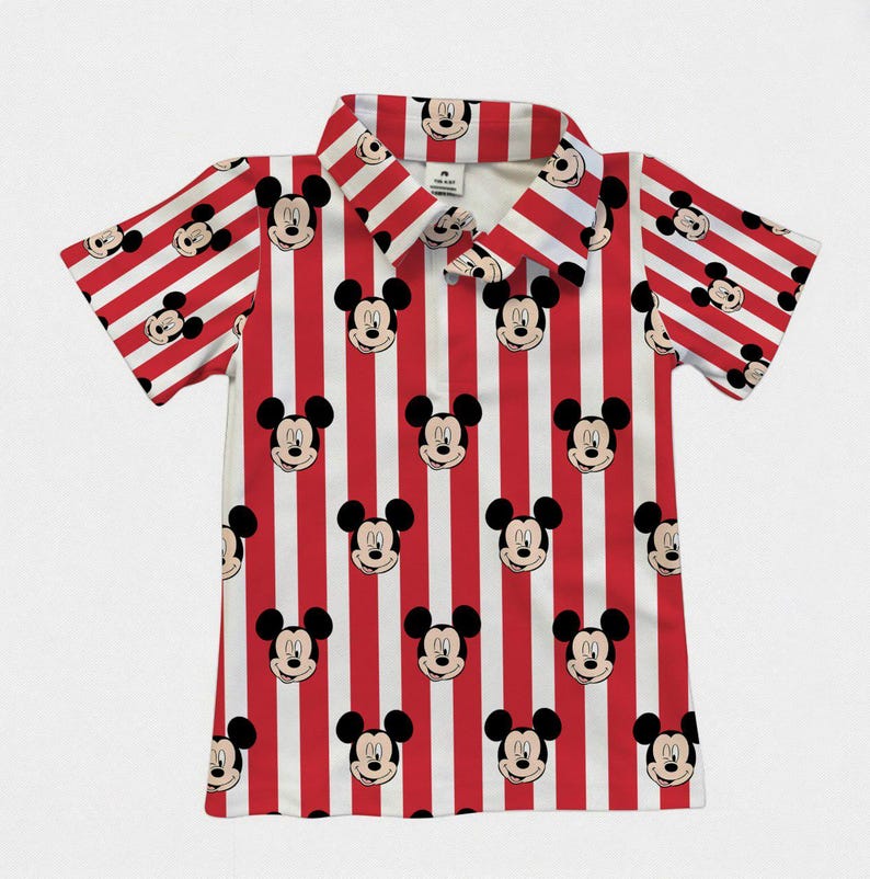 Puede incluir: Camisa de manga corta con cuello y estampado de rayas rojas y blancas. La camisa est&aacute; adornada con im&aacute;genes repetidas de la cara de Mickey Mouse. El dise&ntilde;o es consistente en el cuello y las mangas.