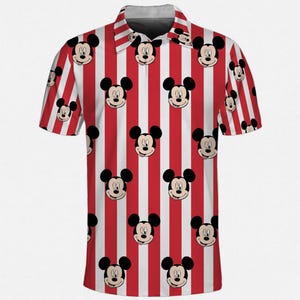 Puede incluir: Un polo de manga corta con un patr&oacute;n repetido de caras de Mickey Mouse sobre un fondo a rayas rojas y blancas. La camisa tiene cuello y cierre de botones. El dise&ntilde;o es una representaci&oacute;n l&uacute;dica y colorida de un personaje de dibujos animados cl&aacute;sico.